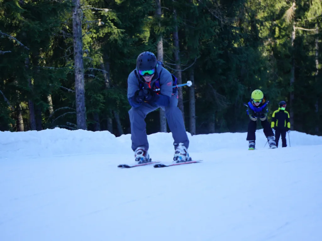 Skifahrer in tiefer Hocke auf der Waldpiste.